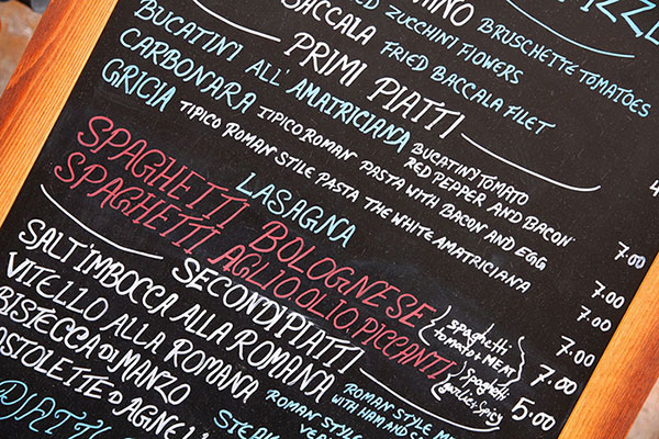 board showing prices of various Italian food menu options