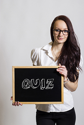 a girl holding up a slate board with quiz written on it