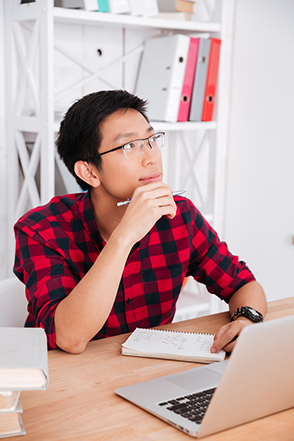 A student with a lap top taking noted at a desk.