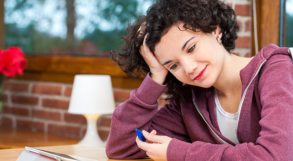 female student working at a desk and looking at her tablet