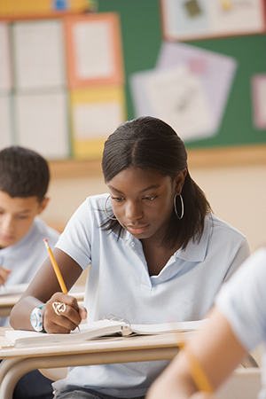 A teenage girl at her desk working on a math problem