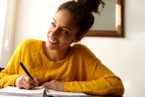 A student working on a notebook, smiling