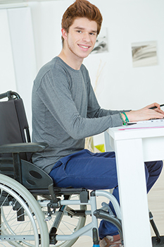 A teenager at a desk in a wheelchair completing algebra homework