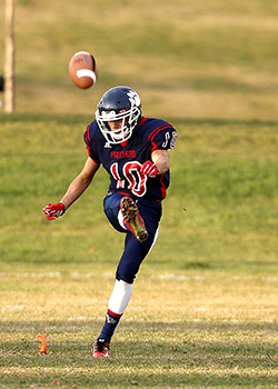 A football player kicking a football of a tee