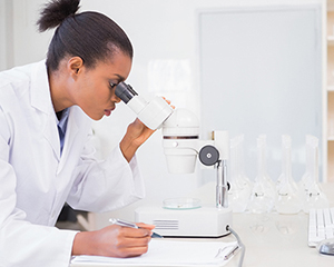 Scientist using microscope and computer