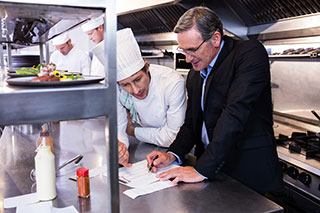 Manager and chef looking at list together in a restaurant kitchen