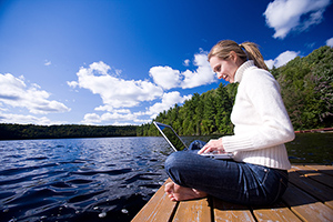 Girl at a computer by a lake