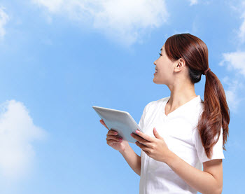 Girl holding tablet looking at clouds