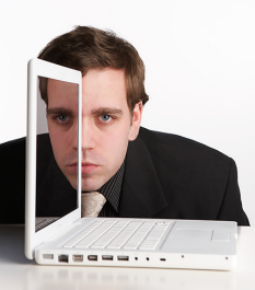 A man's face reflecting on a computer screen