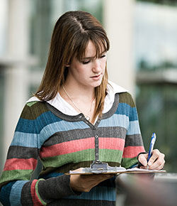 female student writing on a clipboard