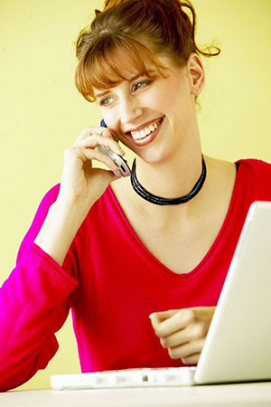 female student talking on phone in front of laptop