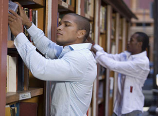 two male students selecting books off of shelves