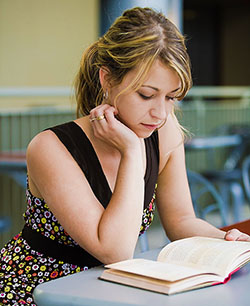 female student sitting at a table reading a book