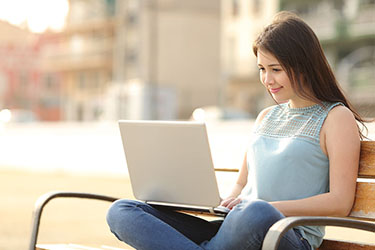 student sitting on a park bench writing