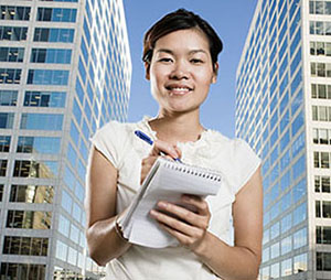 journalist with pen and notepad in front of city skyscrapers