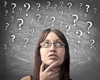 girl thinking with question marks floating in front of chalk board