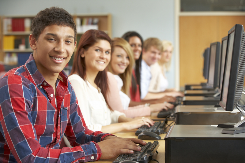 row of studnets smiling and typing on computers