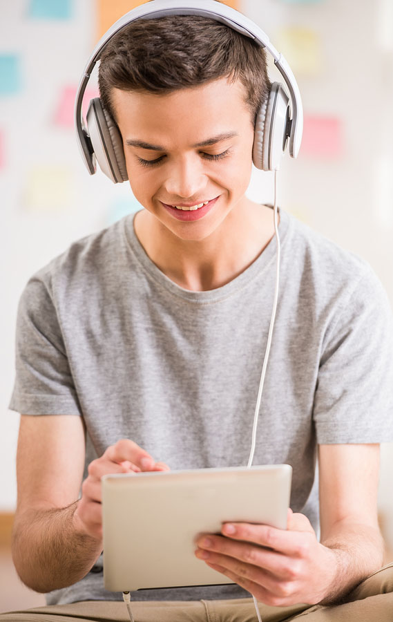 boy with headphones on and tablet in hand