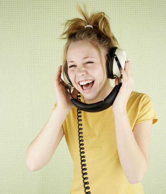 female teen laughing while wearing headphones