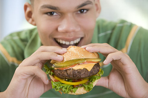 male teen getting ready to bit into a hamburger