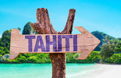 Wooden sign with "Tahiti" written on it and posted by a beach