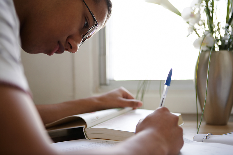 teenage boy writing at a desk