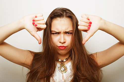 female with hands by her head giving thumbs down