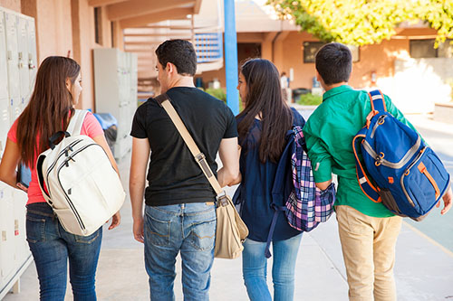 four students walking down the hallway talking