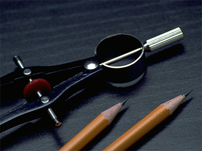 a compass and two pencils on a black desk