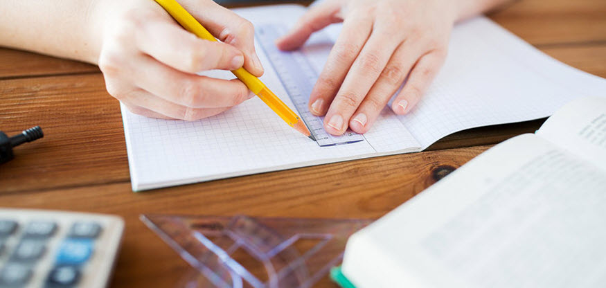 student using a ruler to draw a line on graph paper