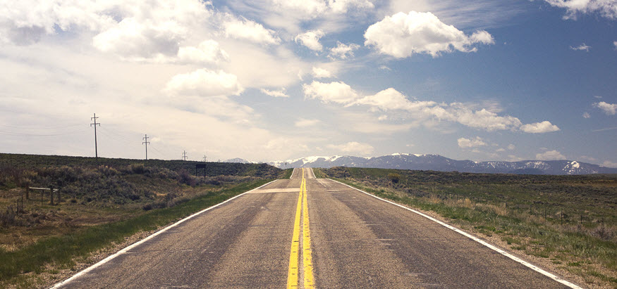 A road with straight lines headed towards a mountain range