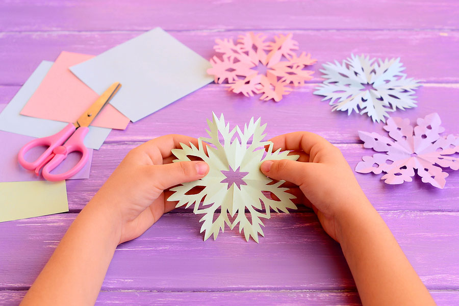 hands unfolding a paper snowflake