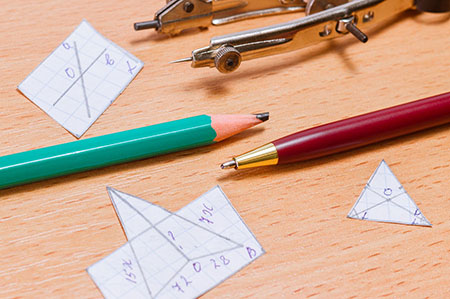 a compass and writing utensils with paper triangles