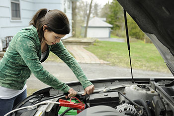 female looking under her car hood