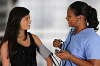 a nurse taking the blood pressue of a female teen