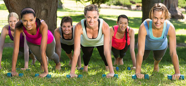 six women doing pushups on dumbbells