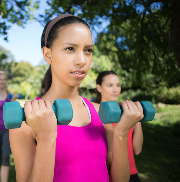 female lifting two free weights in the park