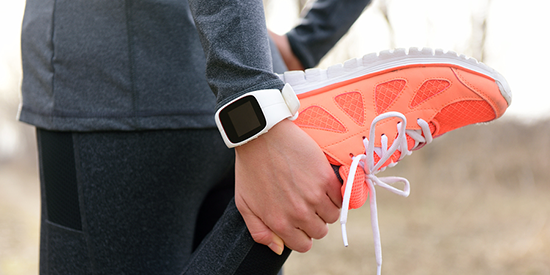 Runner with a fitness watch stretching