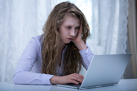 Sad teen looking at a computer screen