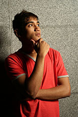 male teen standing against a wall and thinking