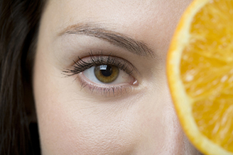 female with an orange slice in front of her face