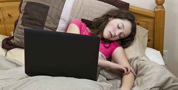 Teenager asleep in bed with laptop