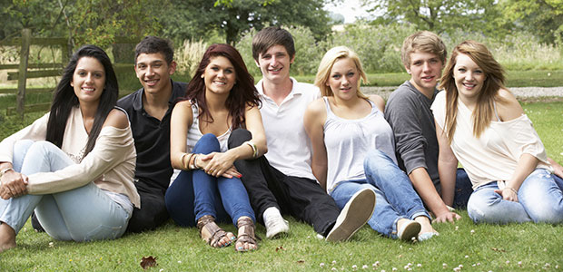 Happy teenagers sitting on grass