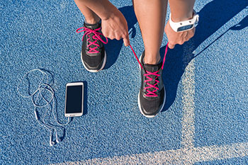 Tying shoes with smartphone and fitness bracelt showing