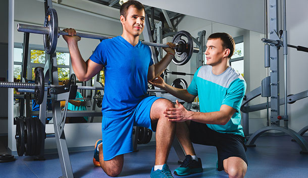 Teenager performing squats with a personal trainer