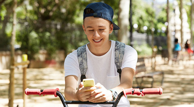 Teenager on a bike without a helmet on a moble device