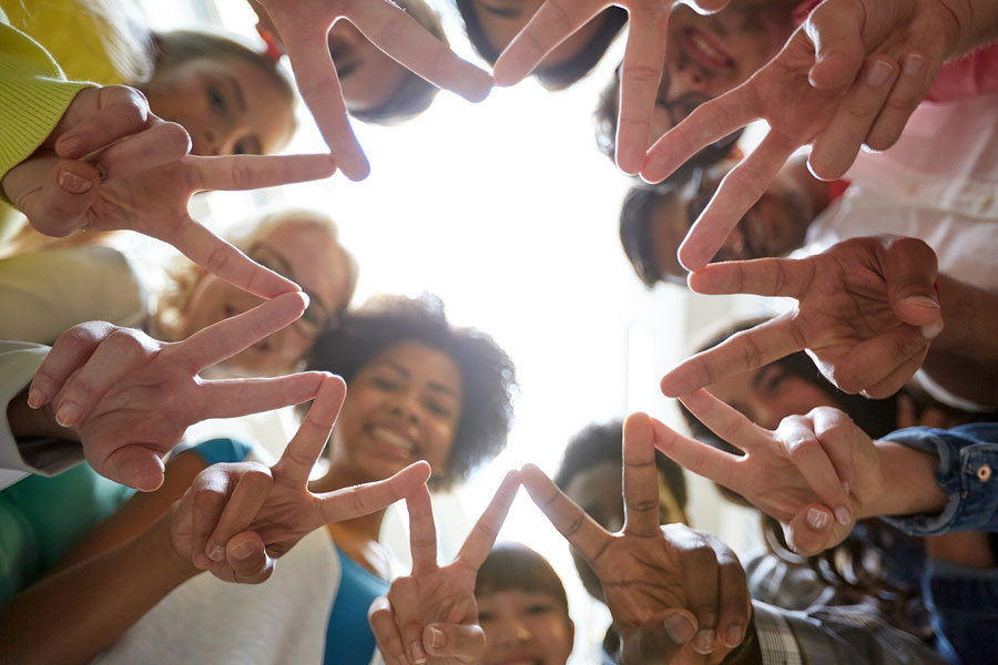 Students standing in circle holding up peace sign fingers