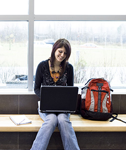 High school girl using a computer near a large window