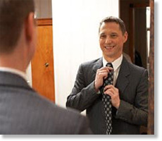 man fixing tie in mirror