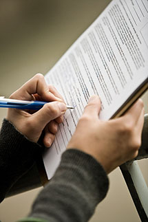 close-up of a hand filling out a form on a clipboard